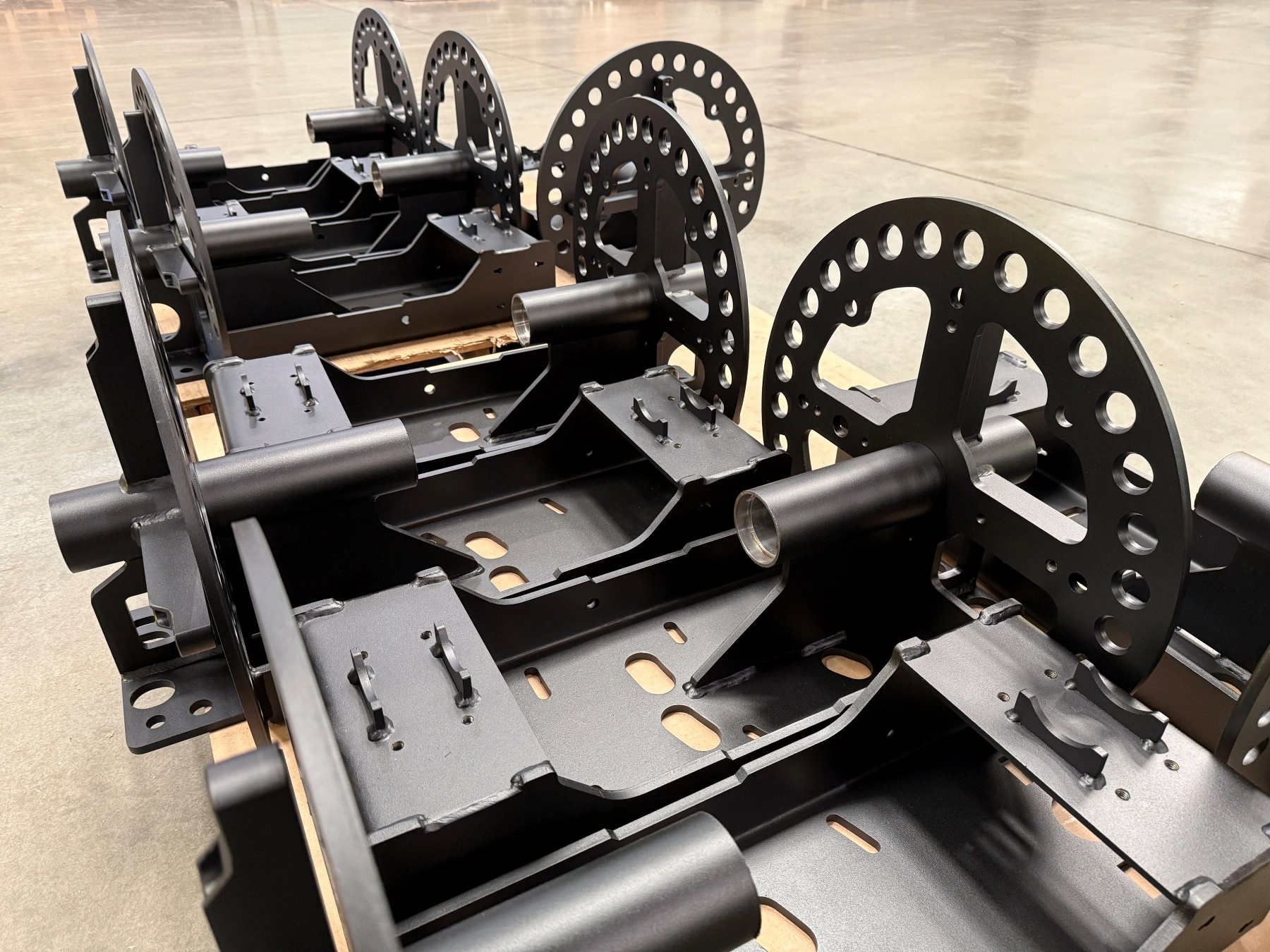 Black powder-coated weldments stacked on pallets