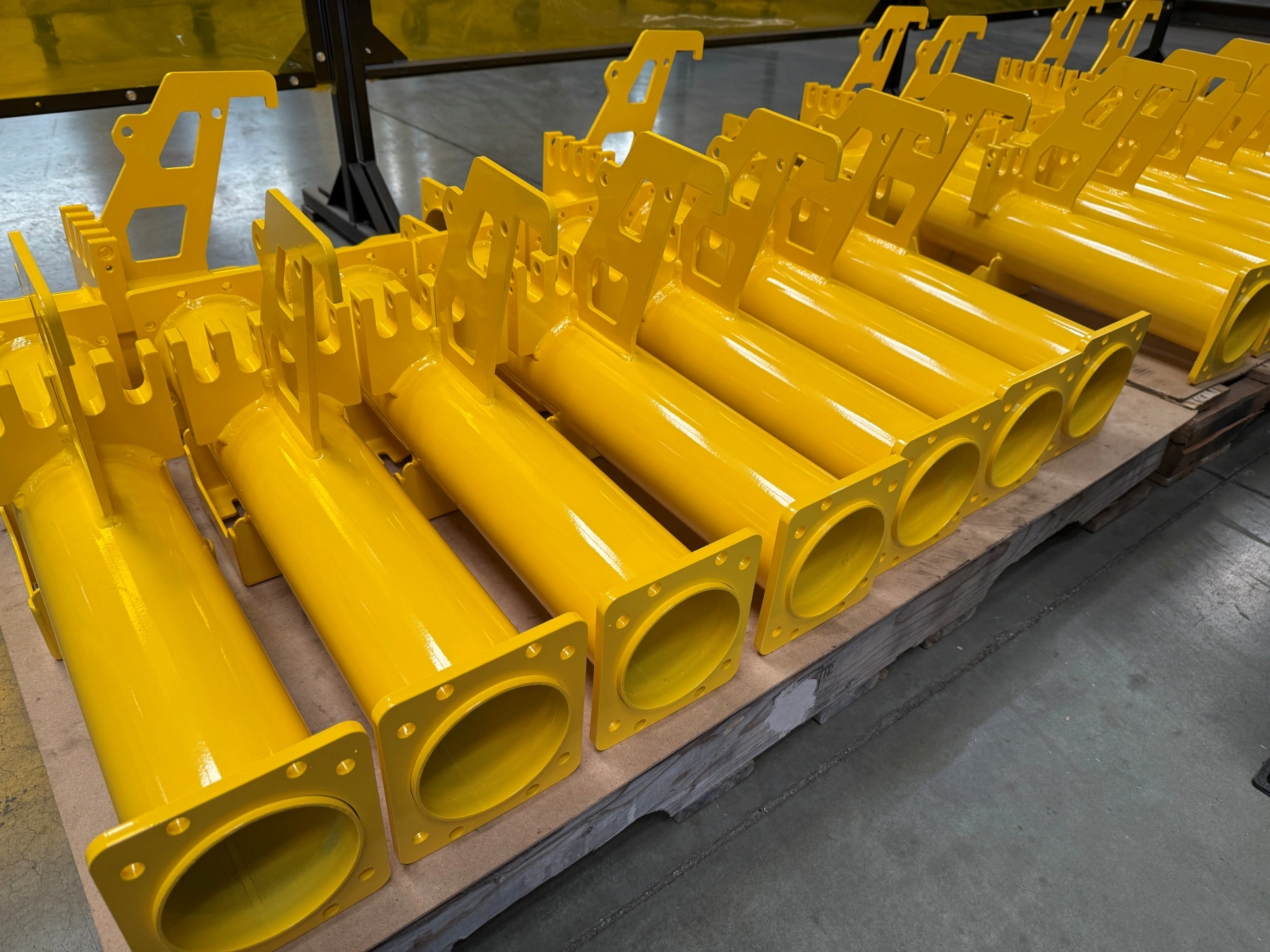 Yellow powder-coated weldments stacked on pallets