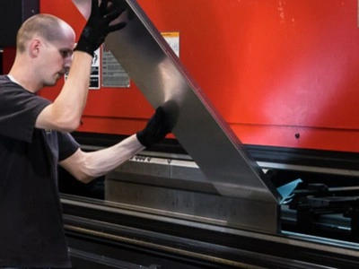 Close-up of a piece of sheet metal being bent with a press brake.