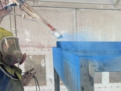A large frame being powder coated with a bright blue color.