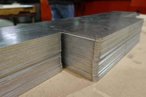 A stack of mid-sized parts cut out of 14-gauge galvanized steel