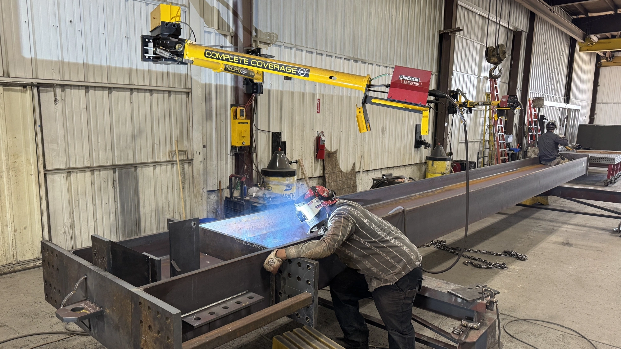 A large structural beam being welded using a WeldPro 360 LRW-18 MIG Welding Boom Arm